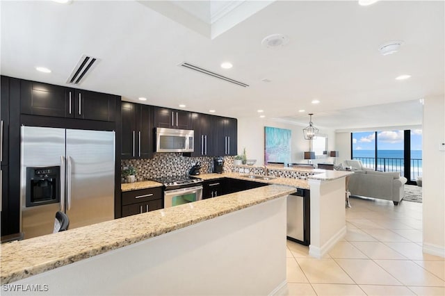 380 Seaview Ct Unit 1505, Marco Island, FL 34145 - kitchen featuring appliances with stainless steel finishes, a peninsula, backsplash, light tile patterned flooring, and light stone counters