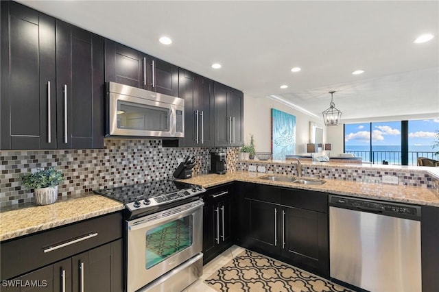 380 Seaview Ct Unit 1505, Marco Island, FL 34145 - kitchen featuring appliances with stainless steel finishes, tasteful backsplash, light stone countertops, dark cabinets, and a peninsula