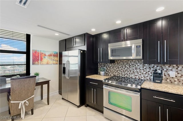 380 Seaview Ct Unit 1505, Marco Island, FL 34145 - kitchen with appliances with stainless steel finishes, decorative backsplash, light tile patterned floors, light stone countertops, and dark cabinetry