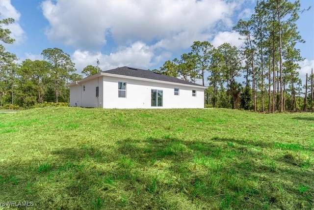 1518 Williams Ave, Lehigh Acres, FL 33972 - rear view of property featuring stucco siding and a lawn