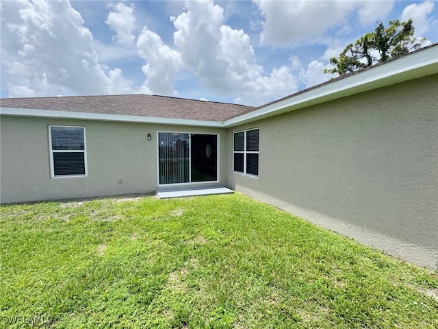 4916 7th St W, Lehigh Acres, FL 33971 - rear view of property featuring stucco siding and a lawn
