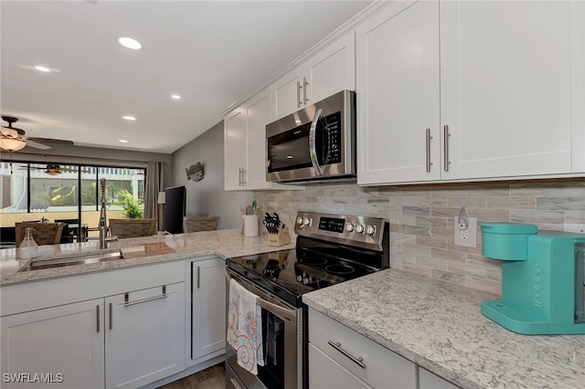 1752 Stickney Point Rd Unit 102, Sarasota, FL 34231 - kitchen featuring stainless steel appliances, white cabinetry, decorative backsplash, light stone counters, and recessed lighting