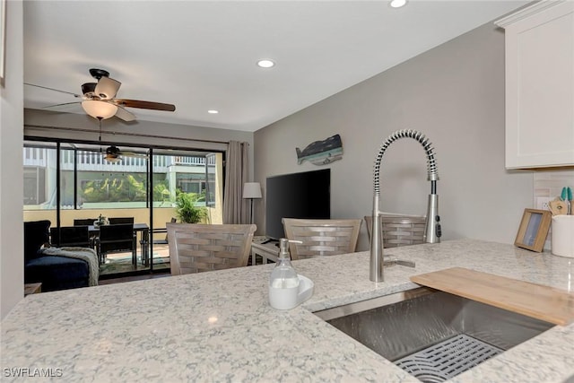 1752 Stickney Point Rd Unit 102, Sarasota, FL 34231 - kitchen with light stone countertops, recessed lighting, a ceiling fan, and white cabinetry