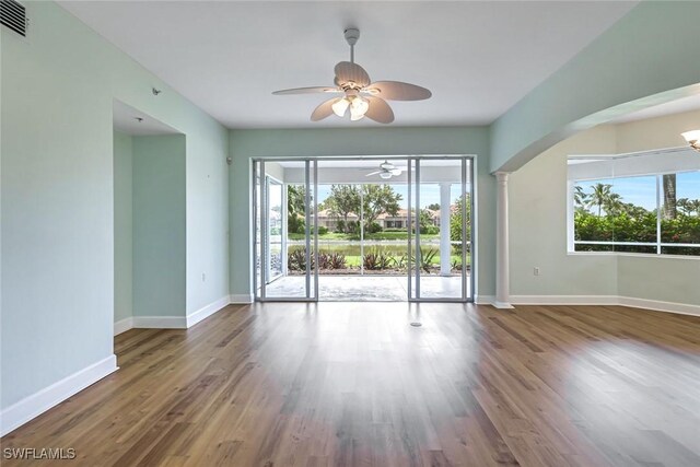 3082 Windsong Ct Unit 303, Naples, FL 34109 - unfurnished room featuring ceiling fan, plenty of natural light, wood finished floors, and arched walkways