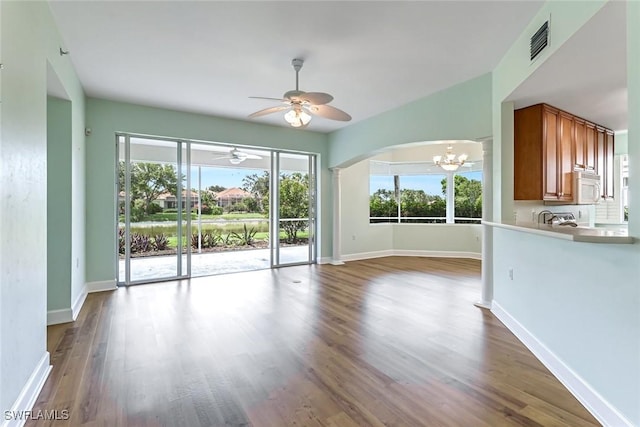 3082 Windsong Ct Unit 303, Naples, FL 34109 - unfurnished living room with a chandelier, arched walkways, ceiling fan, and wood finished floors