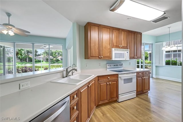 3082 Windsong Ct Unit 303, Naples, FL 34109 - kitchen with white appliances, brown cabinets, light wood-style flooring, ceiling fan, and light countertops