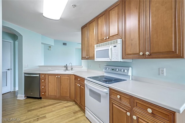 3082 Windsong Ct Unit 303, Naples, FL 34109 - kitchen with white appliances, brown cabinetry, light wood-style flooring, light countertops, and arched walkways