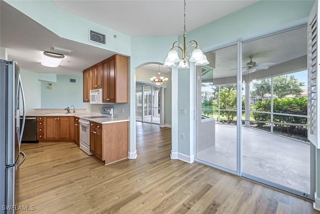 3082 Windsong Ct Unit 303, Naples, FL 34109 - kitchen with appliances with stainless steel finishes, a chandelier, ceiling fan, brown cabinetry, and light countertops