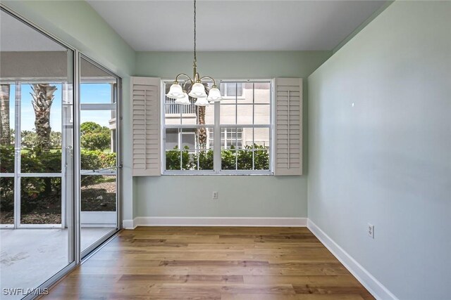 3082 Windsong Ct Unit 303, Naples, FL 34109 - unfurnished dining area with a chandelier, healthy amount of natural light, and wood finished floors