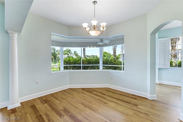 3082 Windsong Ct Unit 303, Naples, FL 34109 - empty room featuring a chandelier, wood finished floors, arched walkways, and ceiling fan