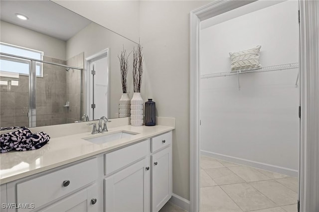 9051 Leatherwood Loop, Lehigh Acres, FL 33936 - bathroom featuring a spacious closet, vanity, a stall shower, and tile patterned flooring