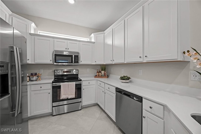 9051 Leatherwood Loop, Lehigh Acres, FL 33936 - kitchen with stainless steel appliances, light countertops, white cabinetry, and light tile patterned floors