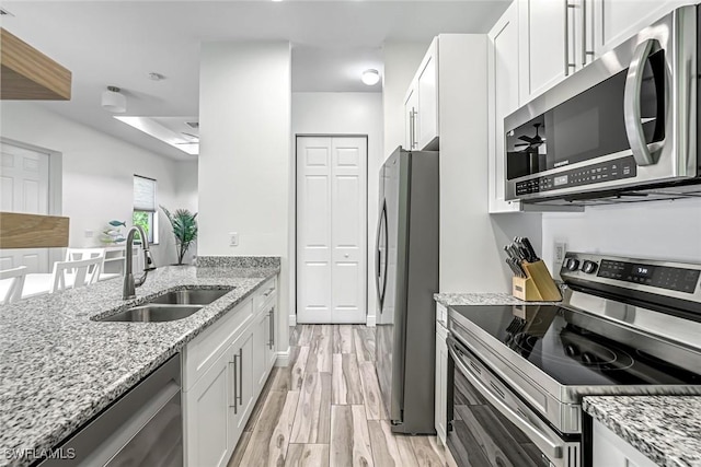 3980 Full Moon Ct, Naples, FL 34112 - kitchen featuring appliances with stainless steel finishes, light wood-type flooring, light stone counters, and white cabinetry