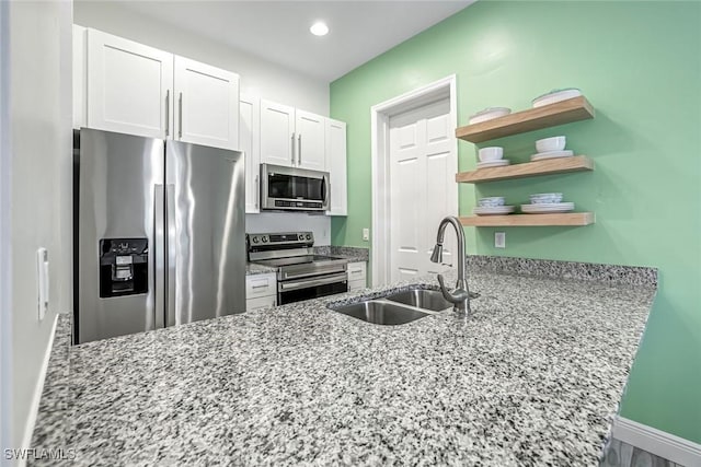 3980 Full Moon Ct, Naples, FL 34112 - kitchen with appliances with stainless steel finishes, open shelves, white cabinetry, light stone countertops, and a peninsula