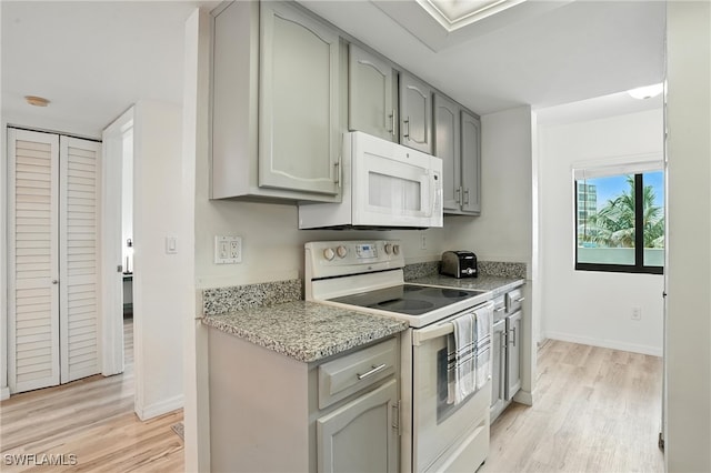 4265 Bay Beach Ln Unit 226, Fort Myers Beach, FL 33931 - kitchen featuring white appliances, gray cabinetry, light wood finished floors, and light stone countertops