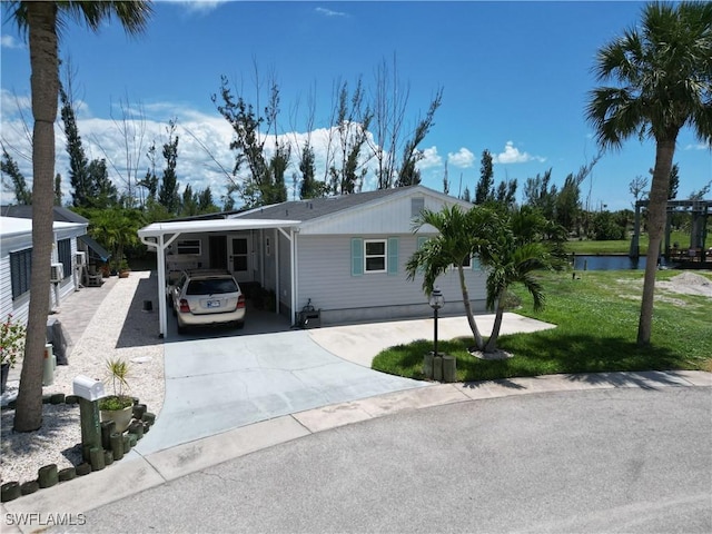 17921 Stevens Blvd, Fort Myers Beach, FL 33931 - view of front facade with concrete driveway, an attached carport, and a front yard