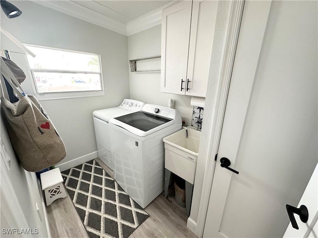 17921 Stevens Blvd, Fort Myers Beach, FL 33931 - laundry area featuring washer and clothes dryer, light wood-style floors, crown molding, and cabinet space
