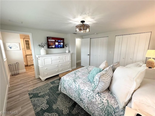 17921 Stevens Blvd, Fort Myers Beach, FL 33931 - bedroom featuring multiple closets, wood finished floors, and a chandelier