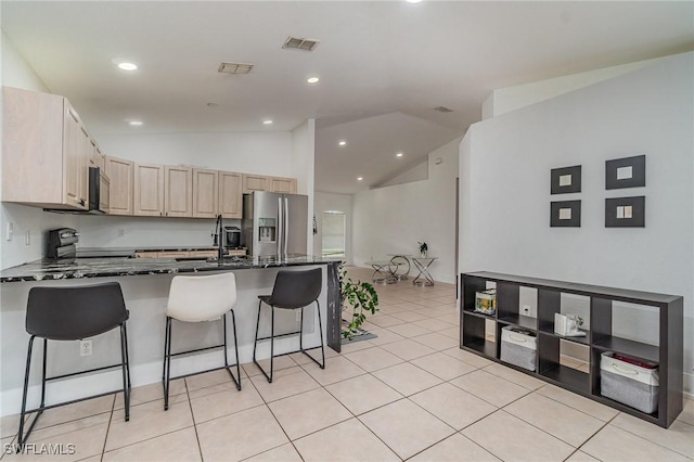 3430 35th Ave NE, Naples, FL 34120 - kitchen with stainless steel fridge with ice dispenser, a peninsula, light brown cabinets, a breakfast bar area, and lofted ceiling
