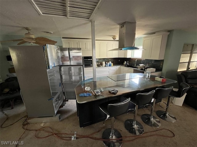 1262 Joerin Ave, North Fort Myers, FL 33903 - kitchen with island exhaust hood, freestanding refrigerator, white cabinetry, stainless steel oven, and backsplash