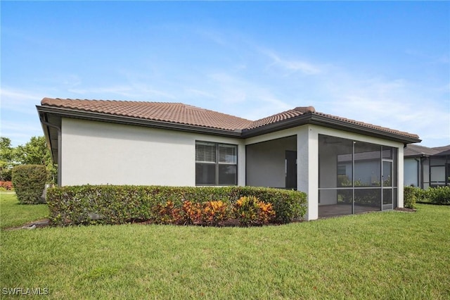 17215 Hadlow Pl, Fort Myers, FL 33967 - back of house featuring a yard, a tile roof, a sunroom, and stucco siding