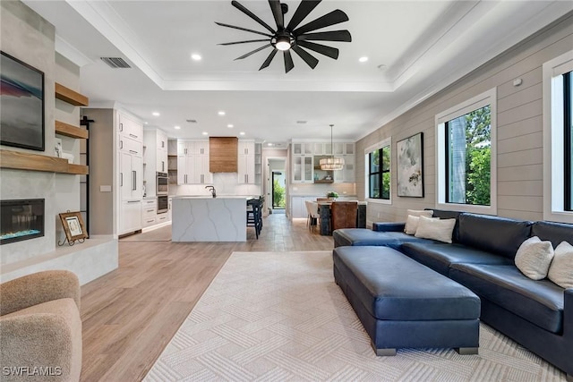 234 Legacy Ct, Naples, FL 34110 - living room featuring a tray ceiling, a ceiling fan, light wood-style flooring, a premium fireplace, and recessed lighting