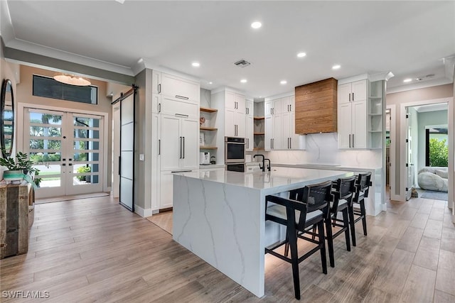 234 Legacy Ct, Naples, FL 34110 - kitchen with open shelves, ornamental molding, premium range hood, double oven, and white cabinetry
