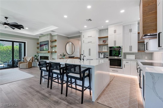 234 Legacy Ct, Naples, FL 34110 - kitchen with open shelves, black electric cooktop, crown molding, double oven, and open floor plan