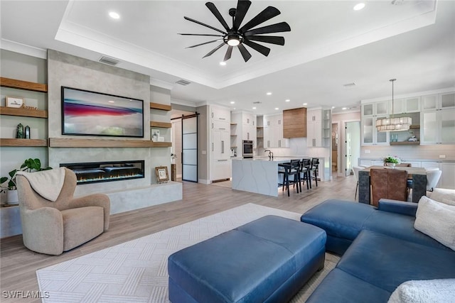 234 Legacy Ct, Naples, FL 34110 - living area featuring a tray ceiling, ceiling fan, light wood finished floors, crown molding, and recessed lighting