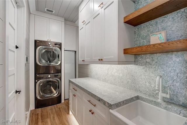 234 Legacy Ct, Naples, FL 34110 - washroom featuring stacked washer / drying machine, light wood finished floors, and cabinet space