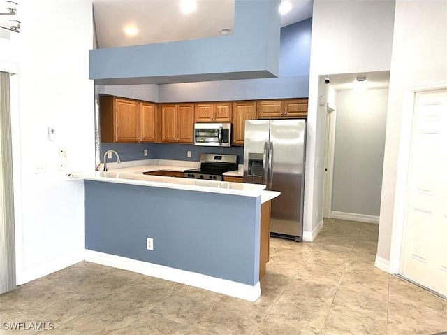 200 W 17th St, Lehigh Acres, FL 33972 - kitchen with appliances with stainless steel finishes, a high ceiling, brown cabinetry, a peninsula, and light countertops