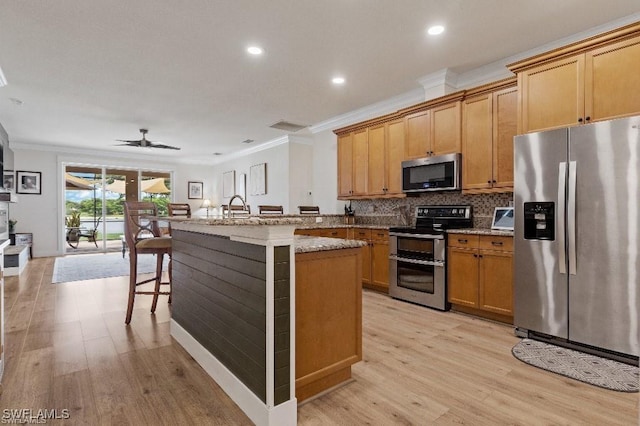 12455 Muddy Creek Ln, Fort Myers, FL 33913 - kitchen with appliances with stainless steel finishes, ornamental molding, light wood-style floors, ceiling fan, and a breakfast bar