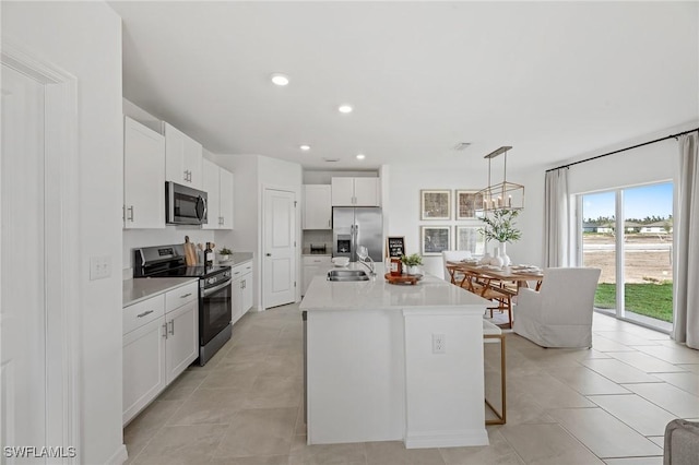 17251 Monte Isola Way N, Fort Myers, FL 33917 - kitchen with appliances with stainless steel finishes, white cabinets, light countertops, an island with sink, and hanging light fixtures