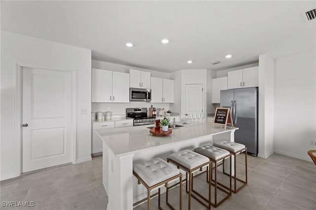 17251 Monte Isola Way N, Fort Myers, FL 33917 - kitchen with appliances with stainless steel finishes, white cabinets, a kitchen breakfast bar, a kitchen island with sink, and recessed lighting