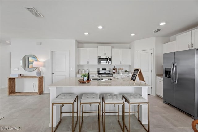 17251 Monte Isola Way N, Fort Myers, FL 33917 - kitchen with stainless steel appliances, a kitchen bar, white cabinetry, light countertops, and recessed lighting