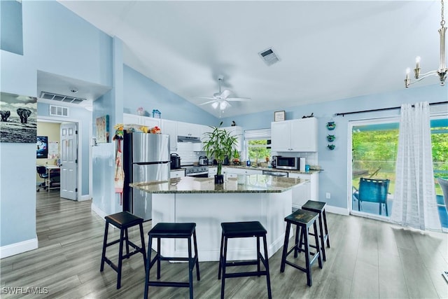 4402 Ruth Ave S, Lehigh Acres, FL 33976 - kitchen with stainless steel appliances, white cabinets, light wood-style floors, a ceiling fan, and a center island