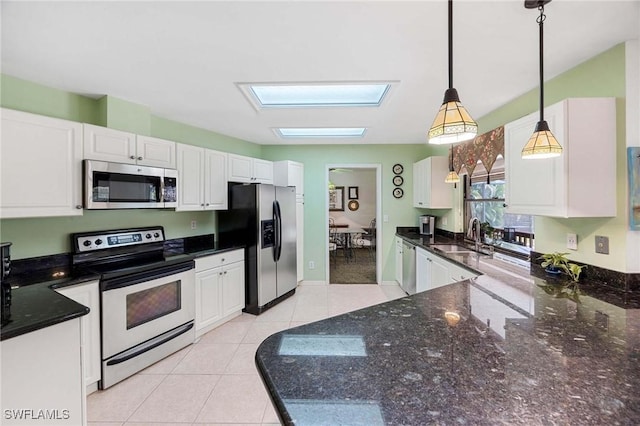 116 Sharwood Dr, Naples, FL 34110 - kitchen with stainless steel appliances, a skylight, white cabinetry, and decorative light fixtures