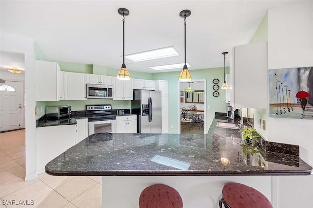 116 Sharwood Dr, Naples, FL 34110 - kitchen with appliances with stainless steel finishes, a peninsula, light tile patterned floors, white cabinetry, and dark stone counters