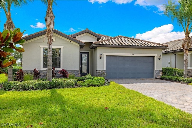 19368 Elston Way, Estero, FL 33928 - view of front facade featuring stone siding, decorative driveway, a garage, stucco siding, and a front lawn