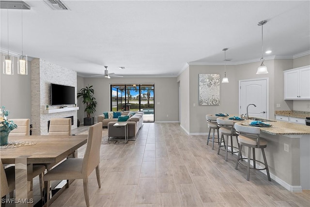 19368 Elston Way, Estero, FL 33928 - dining space featuring a ceiling fan, light wood-type flooring, crown molding, a fireplace, and recessed lighting