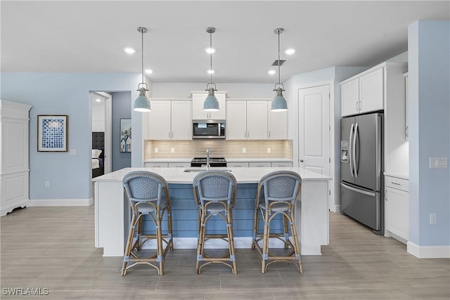 19387 Elston Way, Estero, FL 33928 - kitchen with appliances with stainless steel finishes, light countertops, an island with sink, tasteful backsplash, and white cabinetry