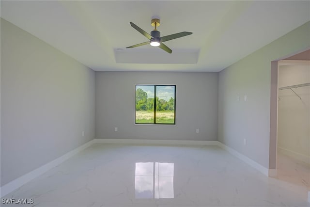 3709 6th St SW, Lehigh Acres, FL 33976 - unfurnished bedroom featuring light marble finish floors, a tray ceiling, a walk in closet, a ceiling fan, and a closet