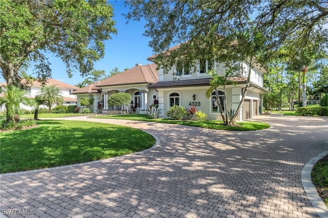 4323 Silver Fox Dr, Naples, FL 34119 - mediterranean / spanish-style house with curved driveway, stucco siding, a garage, and a front lawn
