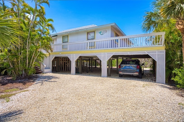 1674 Bunting Ln, Sanibel, FL 33957 - coastal home with gravel driveway, a carport, and stairway