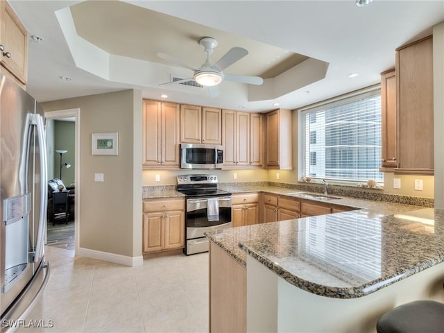 4182 Bay Beach Ln Unit 761, Fort Myers Beach, FL 33931 - kitchen with appliances with stainless steel finishes, a tray ceiling, a peninsula, a breakfast bar, and light stone countertops
