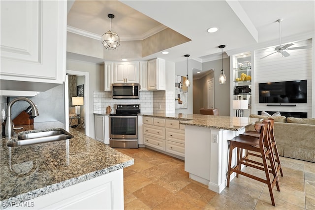 28283 Koi Way, Bonita Springs, FL 34135 - kitchen with appliances with stainless steel finishes, crown molding, a peninsula, tasteful backsplash, and a kitchen bar