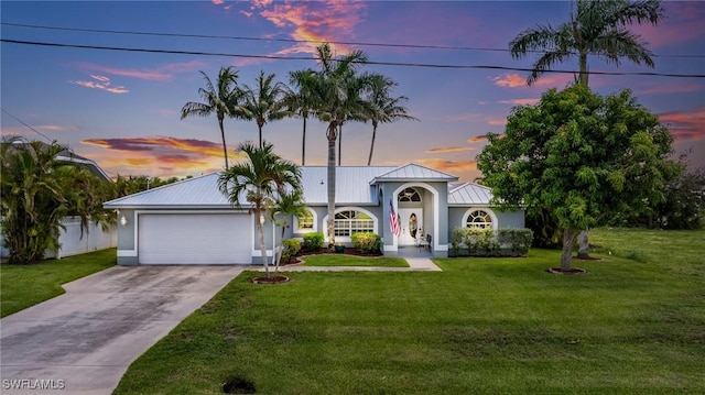 606 Mohawk Pkwy, Cape Coral, FL 33914 - view of front of house featuring a garage, driveway, a front yard, a metal roof, and stucco siding