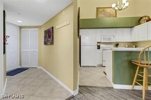 4105 Residence Dr Unit 722, Fort Myers, FL 33901 - kitchen with white microwave, light tile patterned floors, white cabinetry, and range