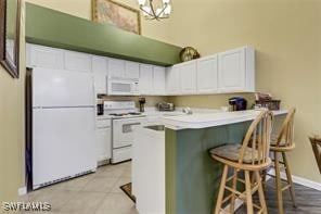 4105 Residence Dr Unit 722, Fort Myers, FL 33901 - kitchen with white appliances, white cabinets, a breakfast bar, and light countertops