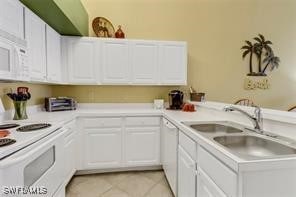 4105 Residence Dr Unit 722, Fort Myers, FL 33901 - kitchen with white appliances, light countertops, light tile patterned floors, and white cabinets